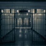 Moody interior of a prison corridor with metal bars, evoking a sense of confinement.